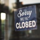 Closeup shot of a blue and white Sorry we are closed wooden signage on glass