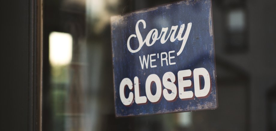 Closeup shot of a blue and white Sorry we are closed wooden signage on glass